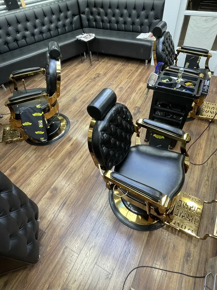 Gold-framed tufted barber chairs on the walnut floor